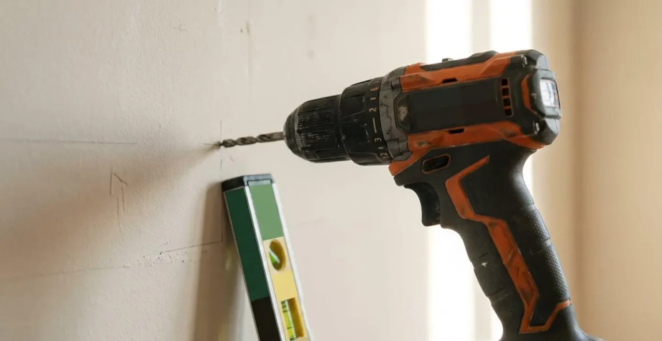 Close-up of a modern drill bit against a domestic wall surface showing the critical moment before potential accidental damage in a home DIY project