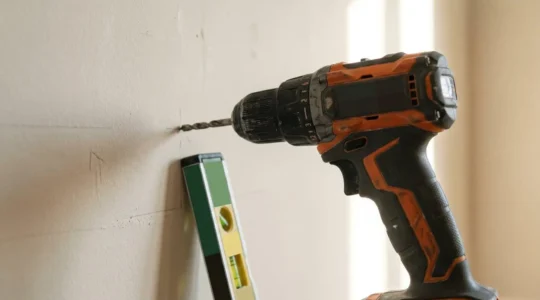 Close-up of a modern drill bit against a domestic wall surface showing the critical moment before potential accidental damage in a home DIY project